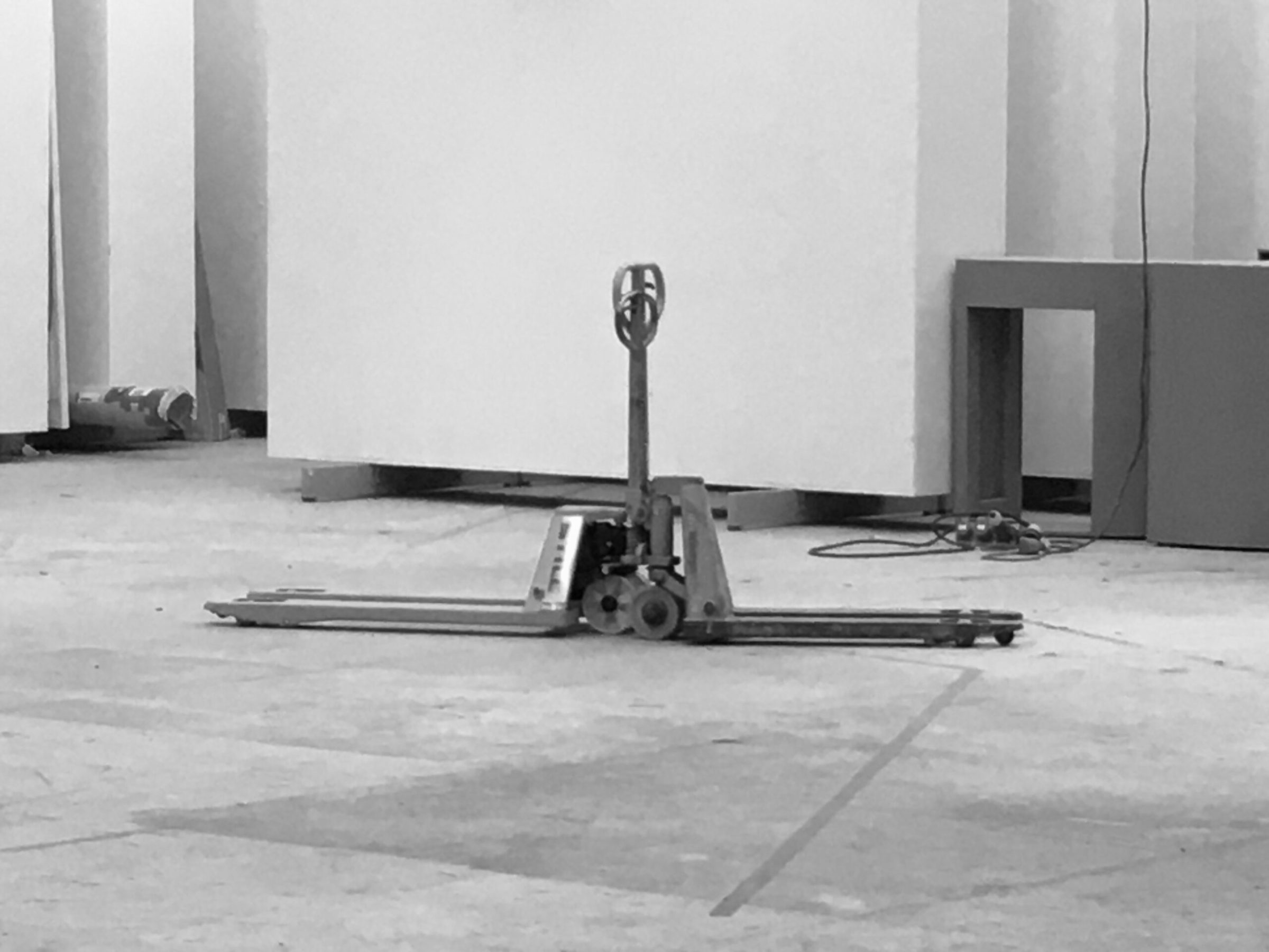 Two pallet jacks standing alone on the concrete floor of an empty gallery